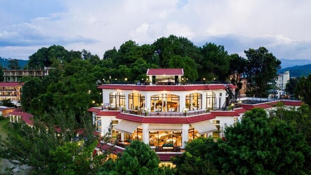 A multi-story hotel with a red roof and white walls, surrounded by lush greenery. - Mirabel Resort (Dhulikhel)