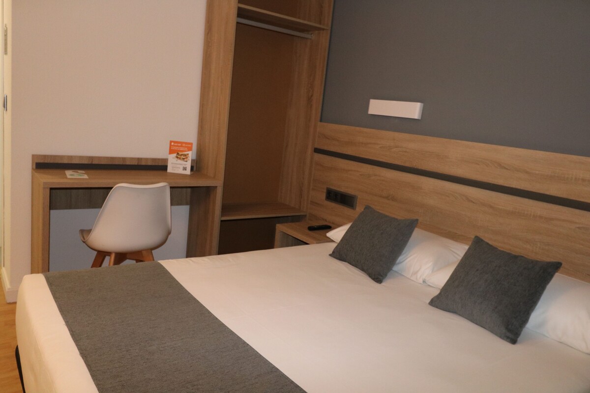 Une chambre d’hôtel avec un lit, un bureau et une chaise.