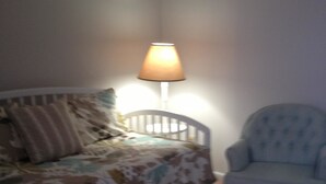 Une chambre à coucher avec un lit, une chaise et une lampe de chevet.