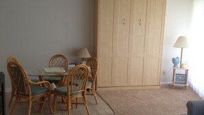 Un salon comprenant une table à manger, des chaises, un canapé, un téléviseur et une armoire.