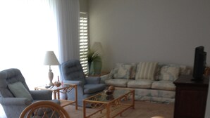 Un salon comprenant un canapé, des fauteuils, une table basse et une table à manger avec des chaises.