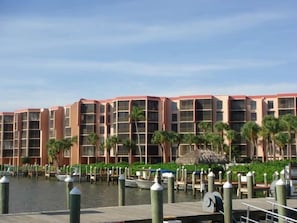 A waterfront hotel with multiple balconies, a dock area, and palm trees. - Riverside B502 (Marco Island)