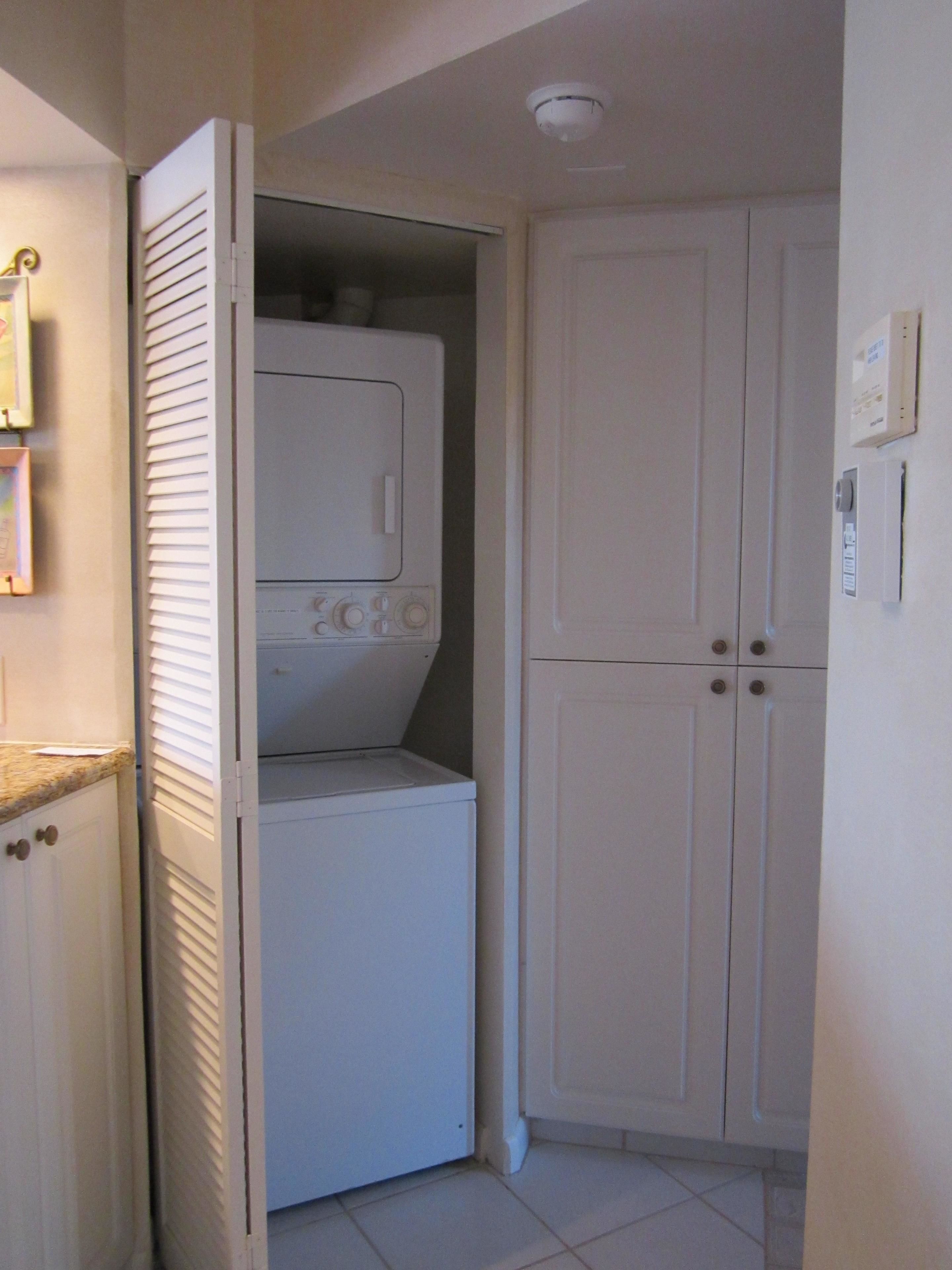 A laundry room with a washer and dryer, a cabinet, and a door with a lock.