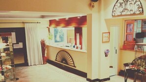 Un vestíbul d'hotel amb una recepció, una presentació de records i una zona de seients.