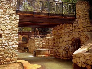 A stone-walled courtyard with a wooden bridge overhead, a small water feature, and a bench. - Terme Acqua Pia Wellness & SPA (Montevago)