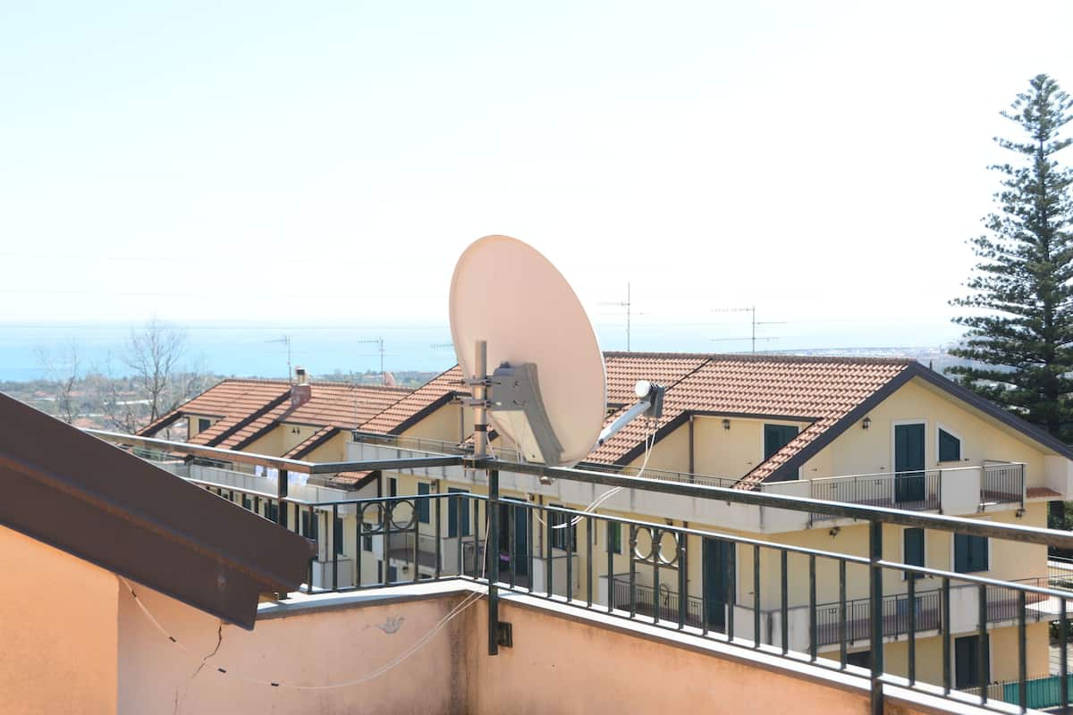 Un edificio residencial con antena parabólica, balcones y vista al mar.