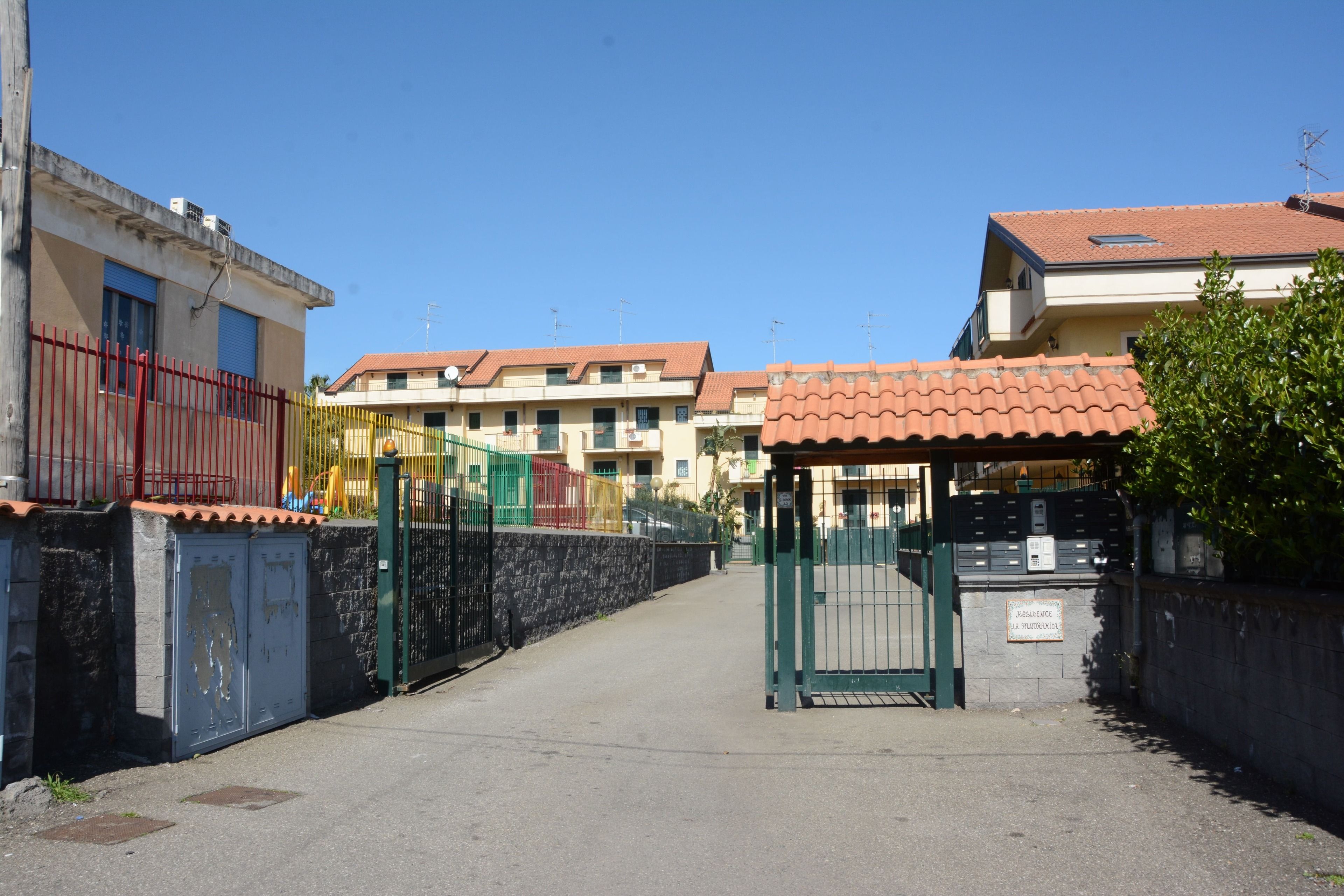 A gated entrance to a residential area with a clear sky.
