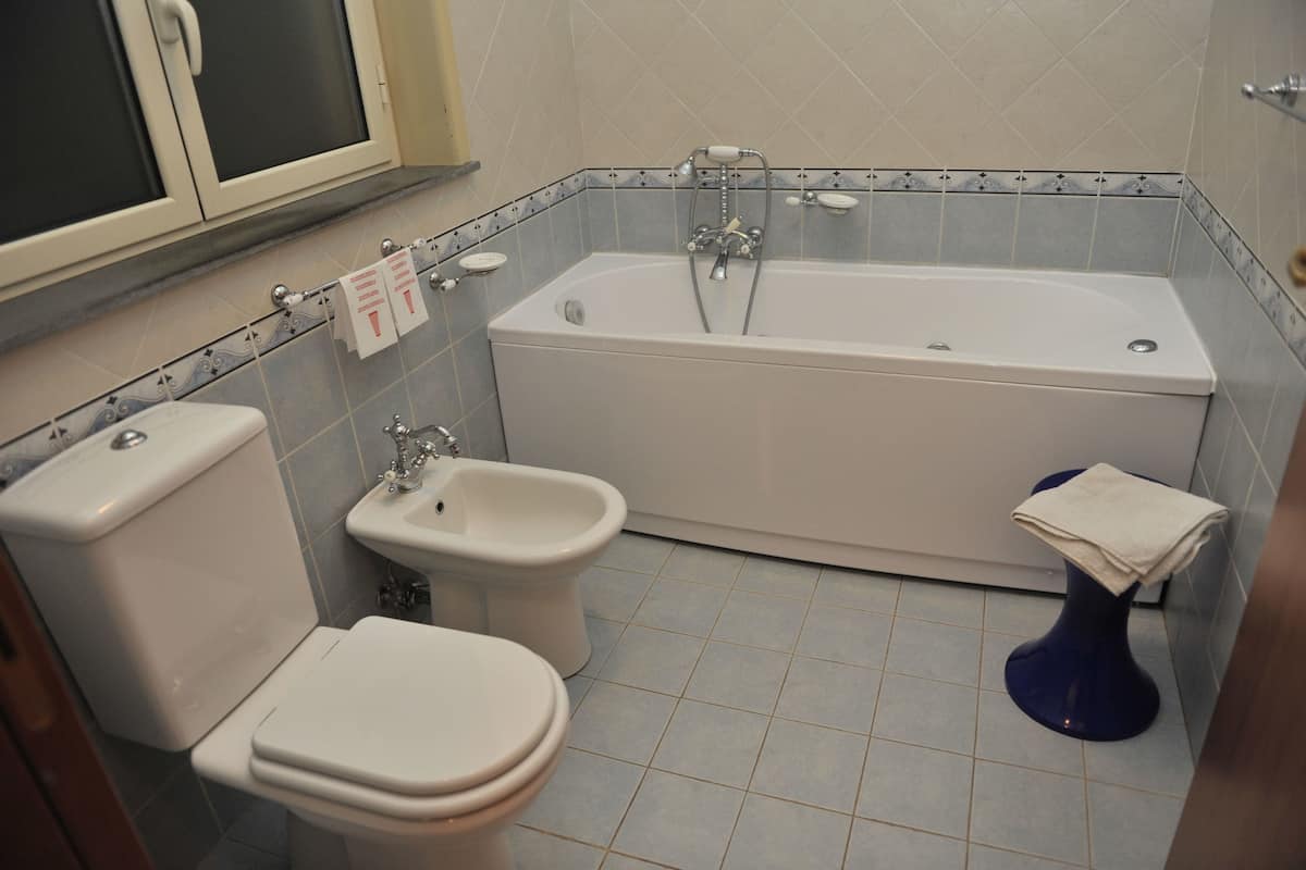 Un baño con bañera, dos inodoros, un bidé y un lavamanos.