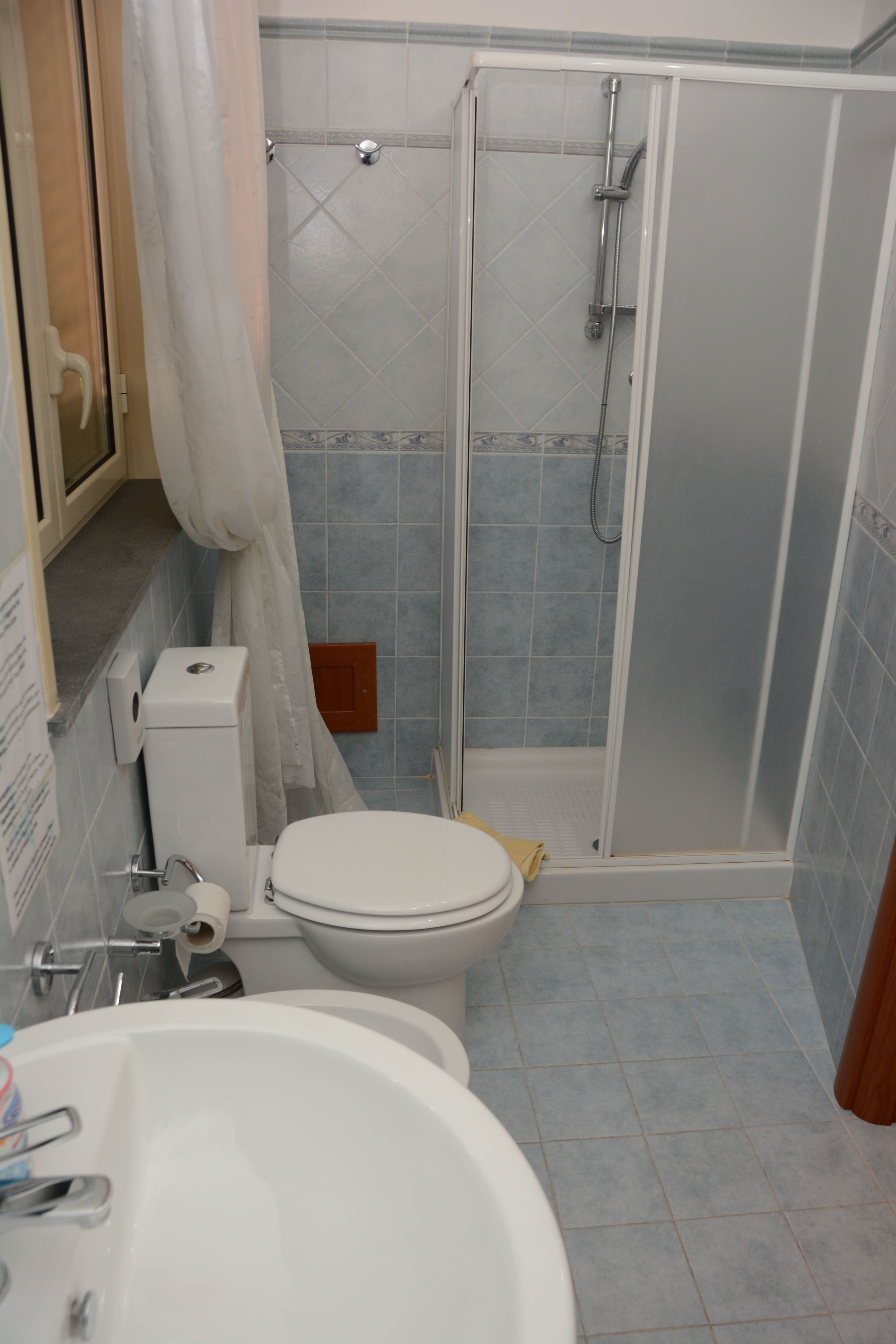 A bathroom with a toilet, sink, and shower area.