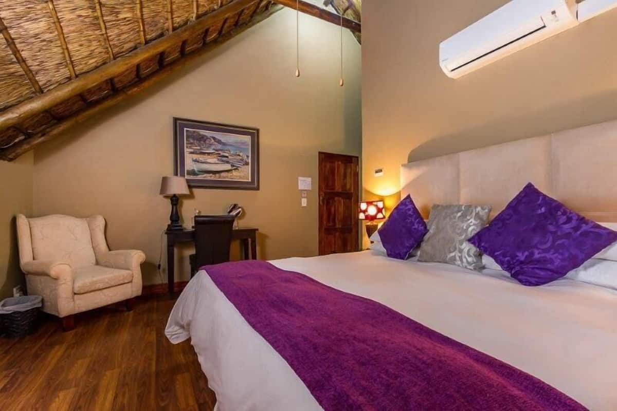 Un dormitorio con cama, una silla, un escritorio, un cuadro y un ventilador de techo.