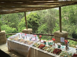 A table set up outdoors with various food items and decorations, surrounded by a natural forest backdrop. - Rainforest Boutique Camp (Krugersdorp)