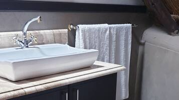 A bathroom with a white sink, dark cabinets, a white toilet, and a wooden ceiling.