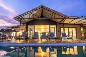 Un edificio moderno con piscina, mobiliario exterior y un patio cubierto.