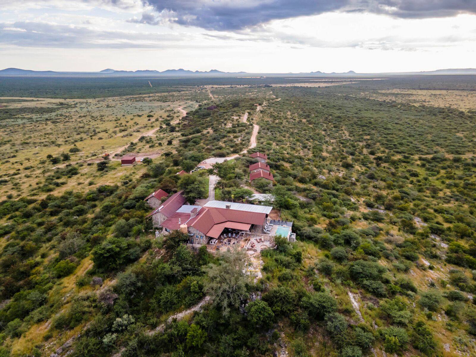 Un hotel extenso y aislado con varias construcciones, una zona de piscina central y un paisaje natural circundante.