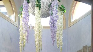 A hallway with a wooden door, two potted plants, hanging floral decorations, a mosaic floor, and a framed picture on the wall. - Antica Isola (Olbia)