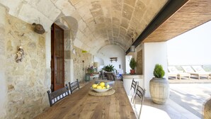 Una habitación con paredes de piedra, una mesa de madera, un cuenco de limones y una planta en maceta.