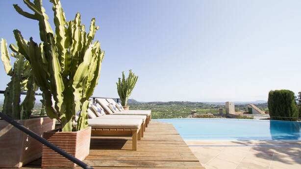 Una terraza de madera con sillones de descanso y una piscina.