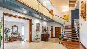Un interior espacioso con una escalera de madera, techo alto y vistas al nivel superior.