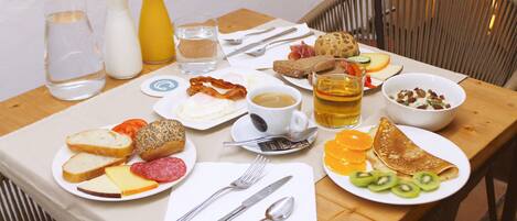 Uma mesa de café da manhã com diversos alimentos, utensílios e bebidas.