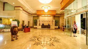 Un vestíbulo de hotel con un mostrador de recepción, una estatua de león y un candelabro.