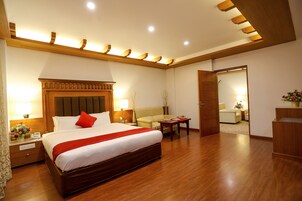 Una habitación de hotel con una cama grande, mesitas de noche, un escritorio, un sofá y un espejo.