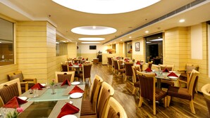 Un comedor amplio con varias mesas y sillas, una barra de servicio central y un diseño moderno de techo.