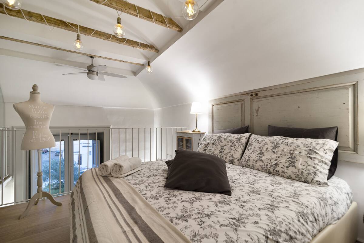 Une chambre à coucher avec un lit, un ventilateur de plafond, une commode et une fenêtre donnant sur un beau paysage.