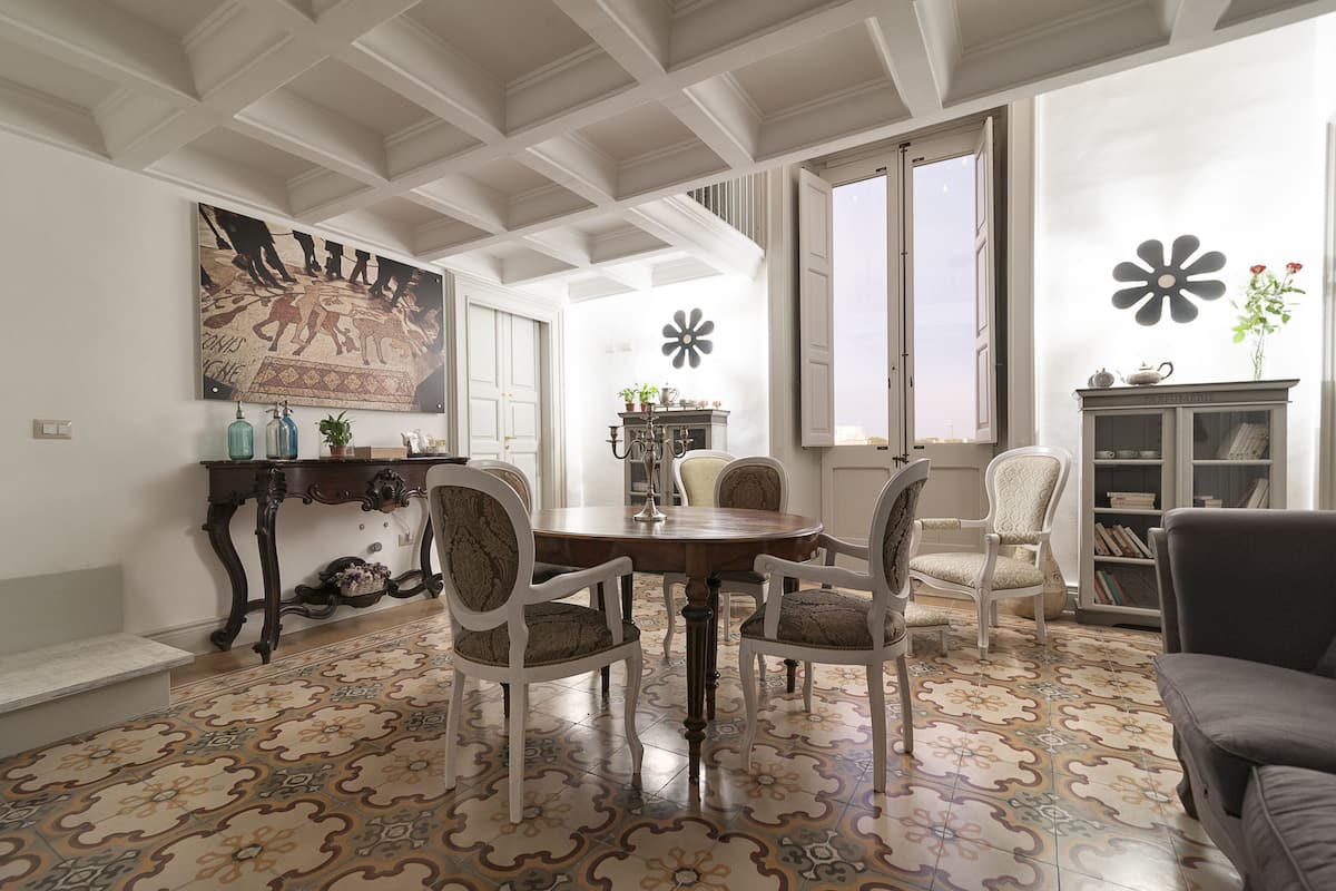 Un coin repas comprenant une table ronde, quatre chaises et un mur décoratif orné d’un motif floral.