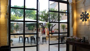 A restaurant with a patio area, outdoor seating, and a stone wall with a decorative light fixture.