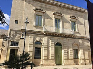 A historic building with a symmetrical facade, large windows, and a green door. - Palazzo Mandurino (Zollino)
