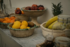 A wooden table with various bowls containing fruits and jars. - Palazzo Mandurino (Zollino)