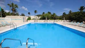 A swimming pool with lounge chairs and palm trees in the background.