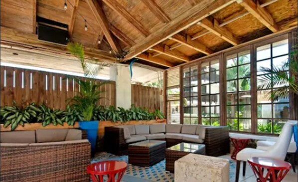 A covered outdoor seating area with a wooden ceiling, large windows, and potted plants. - Sapphire Sanctuary by the Sea (St. Thomas)