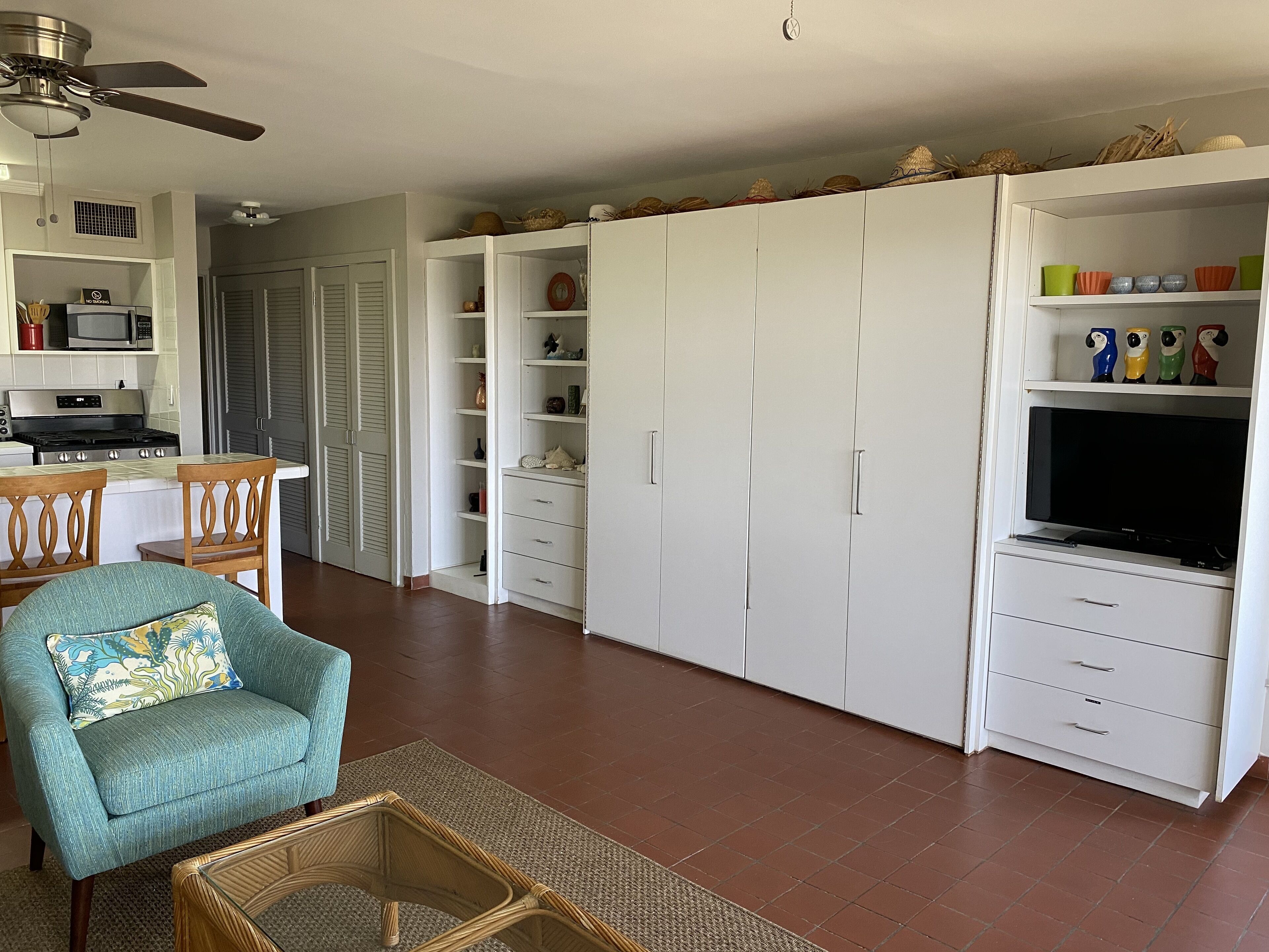A spacious living area with a sofa, a television, and a kitchen area with a microwave and stove.