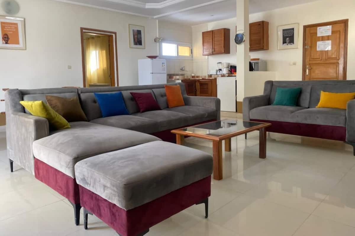 A modern living room with a grey sectional sofa, a coffee table, and a kitchen in the background.