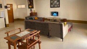 A living room with a grey sofa, wooden coffee table, and a television on the wall. - Residence Les Calanques (Dakar)