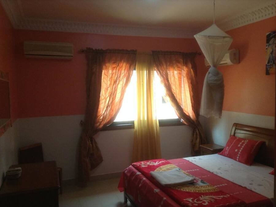 Un dormitorio con cama, cortinas, aire acondicionado y mosquitera.