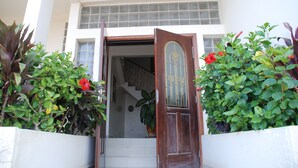 A building entrance with a wooden door, a staircase, and a sign above that reads "RESIDENCES LES CALANQUES". - Residence Les Calanques (Dakar)
