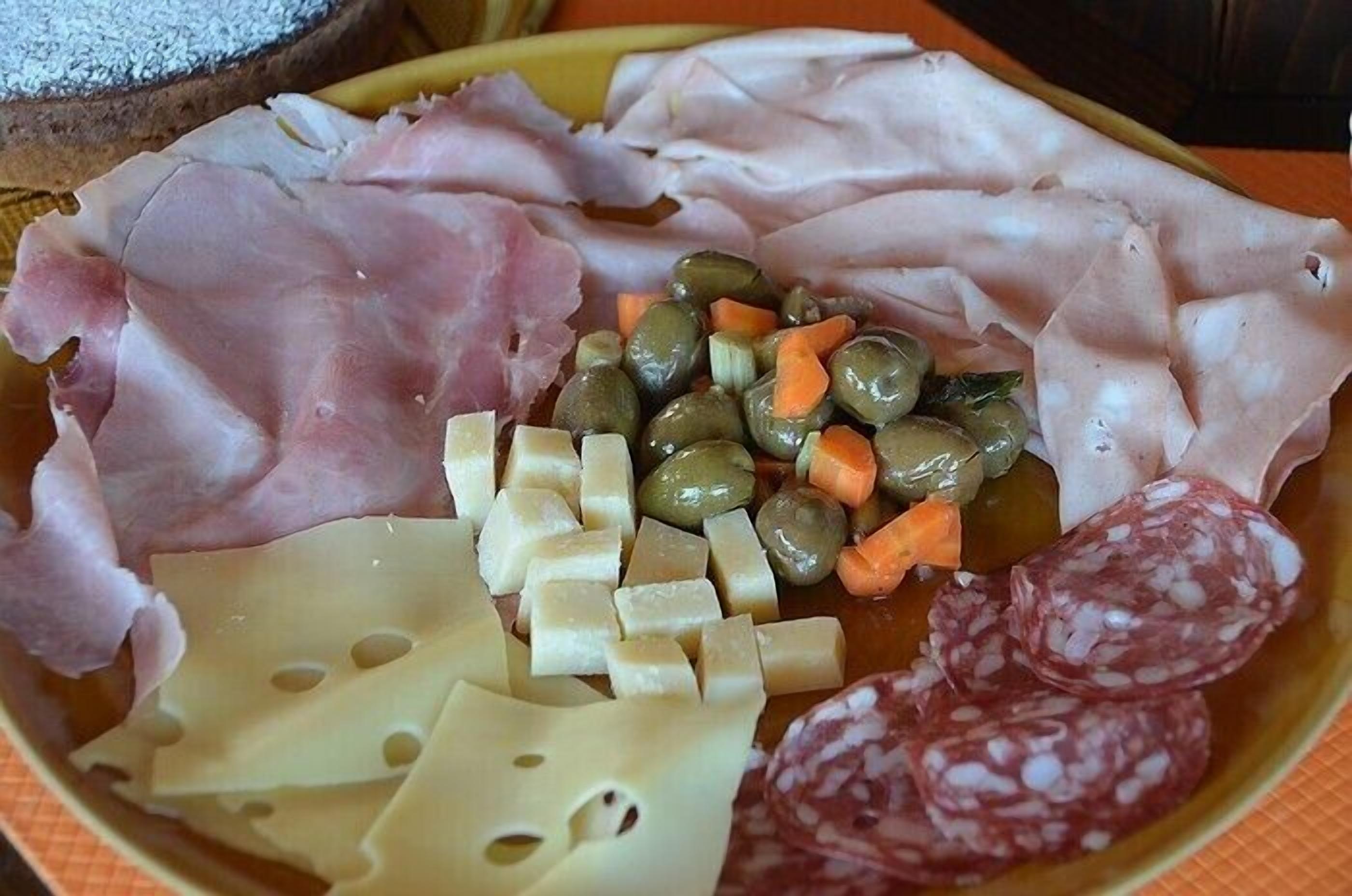 Un tagliere con salumi, formaggi e verdure assortiti.