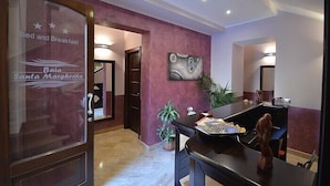 A hotel reception area with a glass door labeled "Baia Santa Margherita" and a desk with a plant and papers. - Baia Santa Margherita B&B (San Vito Lo Capo)