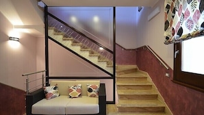 A modern interior with a staircase, a sofa with patterned cushions, and a decorative wall panel. - Baia Santa Margherita B&B (San Vito Lo Capo)