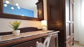 A wooden vanity with a mirror, a potted plant, and a lamp. - Baia Santa Margherita B&B (San Vito Lo Capo)