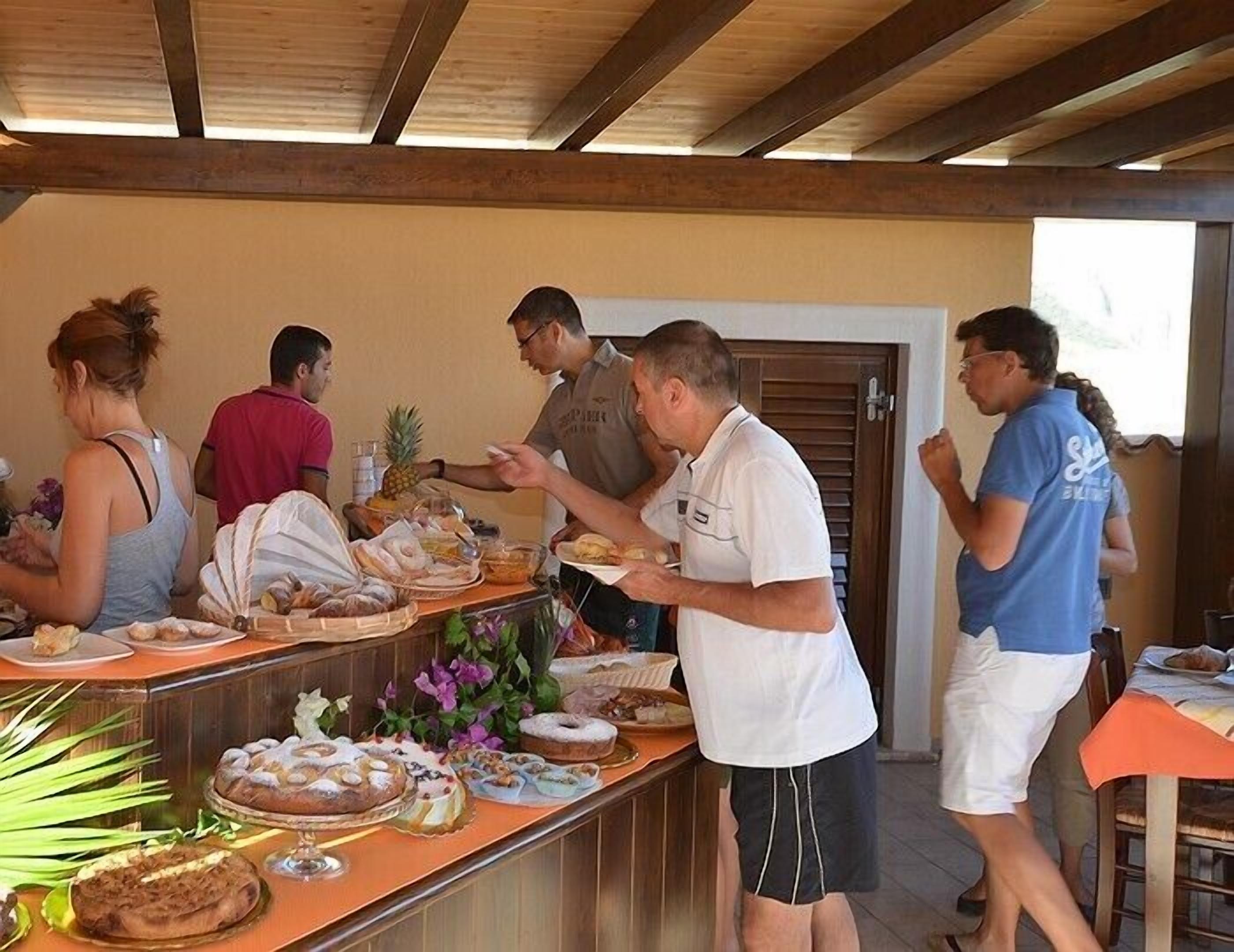 A buffet setup with various food items and a group of people.