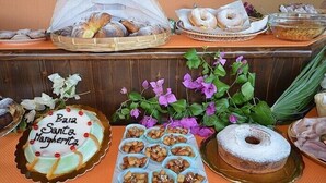 A buffet table with various baked goods, including a cake labeled "Bia Santa Margarrita," and a variety of pastries and bread. - Baia Santa Margherita B&B (San Vito Lo Capo)