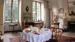 Une salle à manger avec une table mise pour le petit-déjeuner, une cheminée et de grandes fenêtres.
