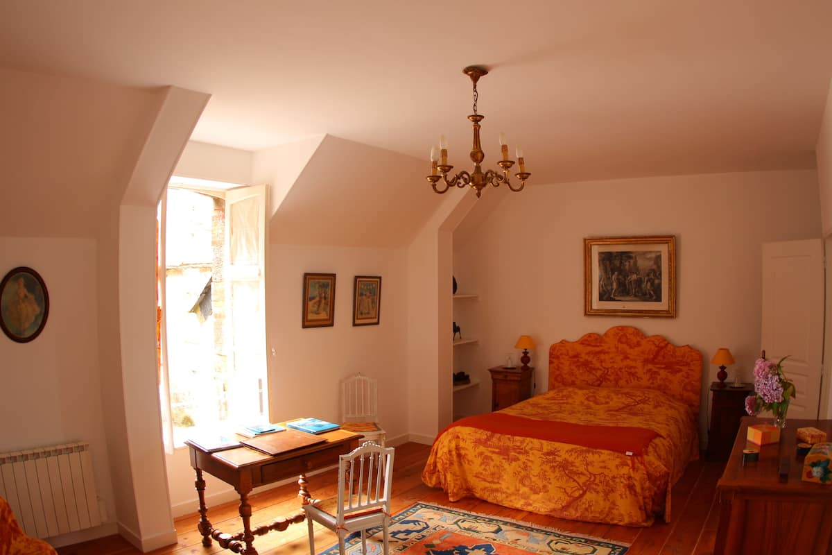 Un dormitorio con una cama grande, un escritorio y una silla. Un candelabro cuelga del techo.
