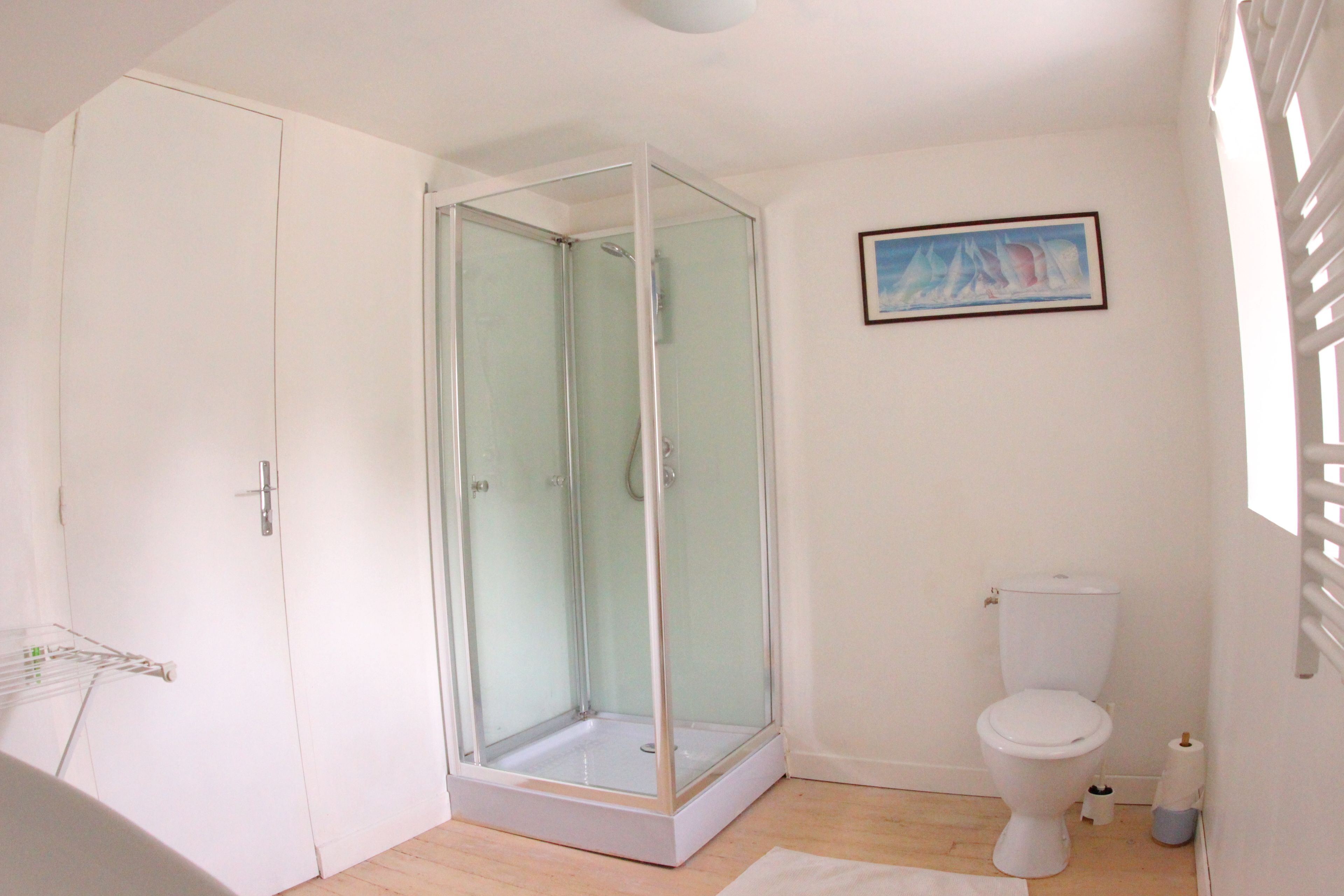 Ein Badezimmer mit einer Duschkabine, einer Toilette und einem gerahmten Bild an der Wand.