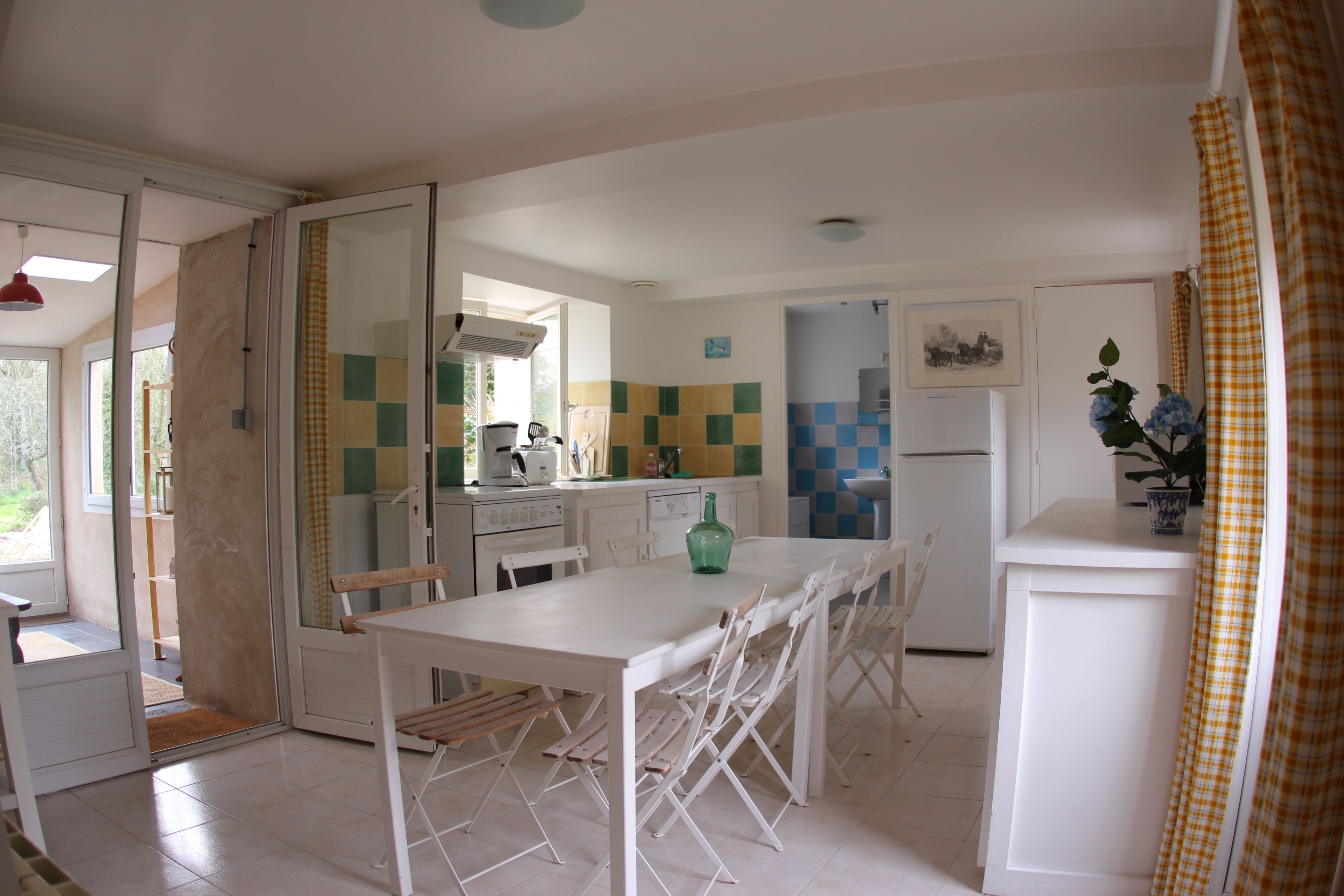 A compact kitchen with a dining table and chairs, a refrigerator, and a sink.