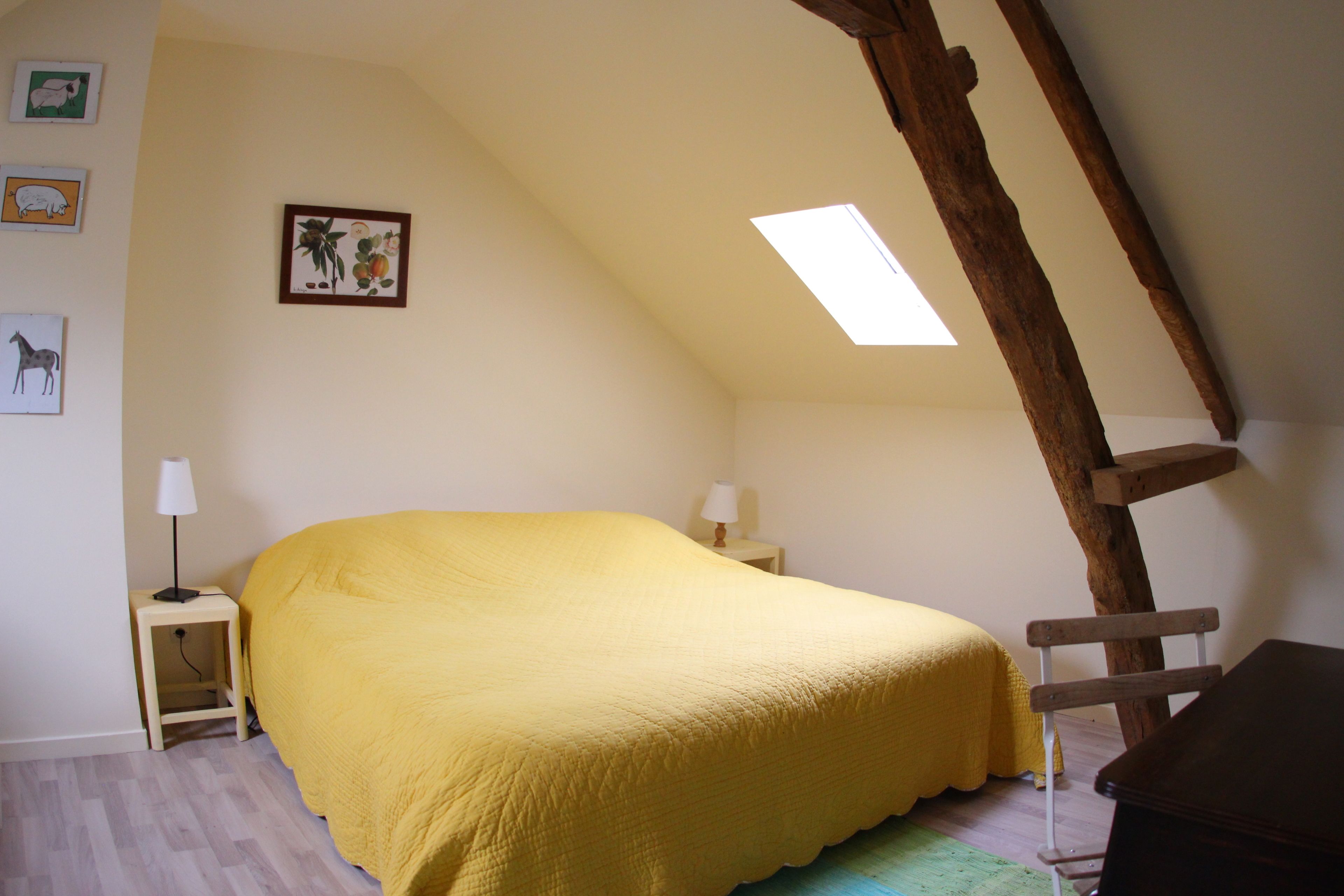 A bedroom with a bed, two bedside tables, a wooden ladder, and a skylight.