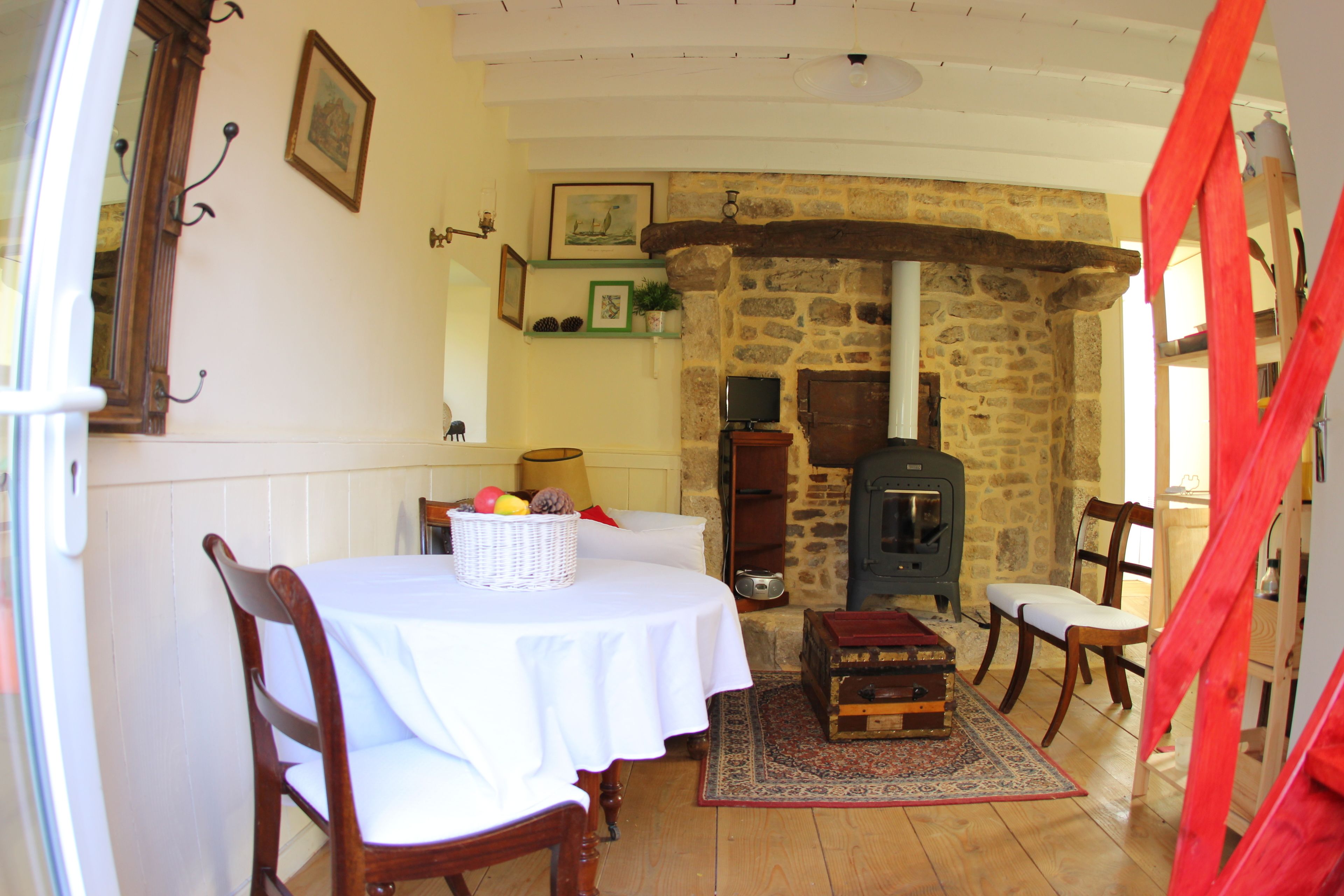 A cozy room with a stone fireplace, a table with a basket of fruit, and a vintage radio.